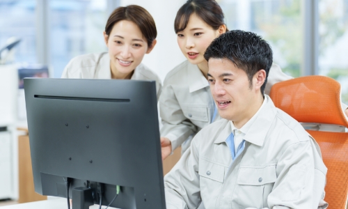 パソコンを操作する作業着をきた男女